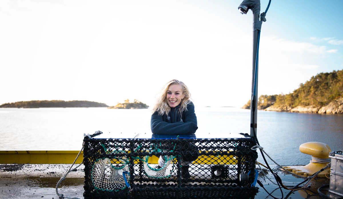 smilende kvinne med stor hummerteine foran seg