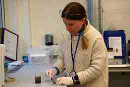 Kvinne på lab med avføringsprøver i to glass.