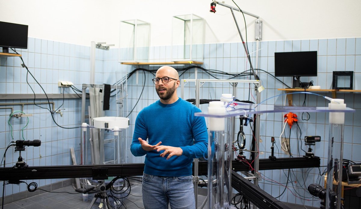 Man in blue sweater and blue jeans in a room with blue tiles and lots of different equipment.
