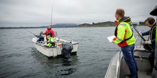 

Menn i liten båt som snakker med person i en annen båt