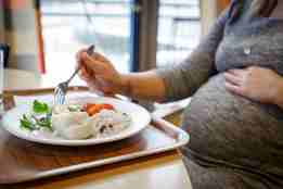gravid kvinne spiser fisk