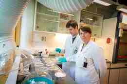 Hilde Elise og Andrey i labfrakk med prøver av laks inne på labben