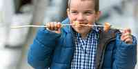 

Foto av gutt  som spiser laks av grillspyd