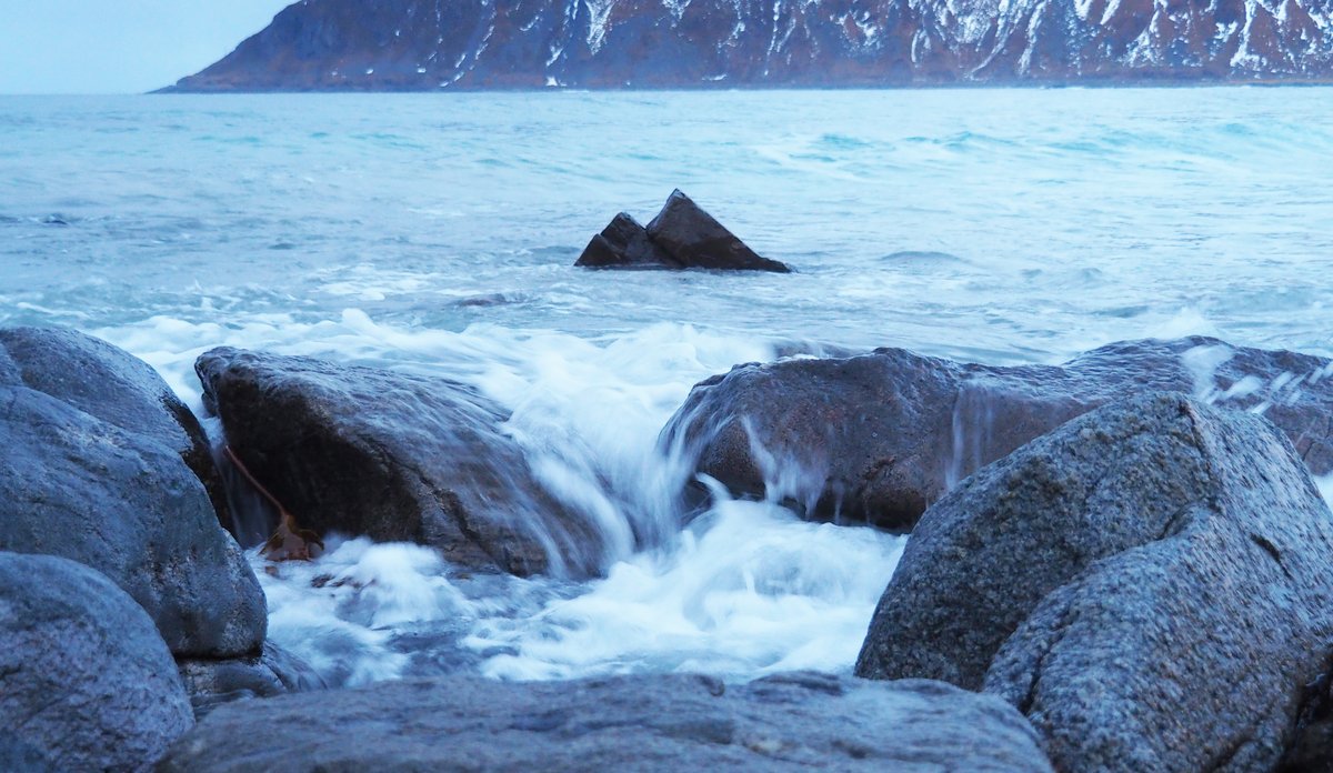 
bølger slår mot grå stein, skummende hvit sjø 