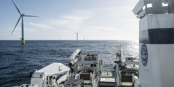 

Utsikt fra broen på et fartøy til sjøs. I horisonten står flere vindmøller til havs.