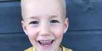 

Nærbilde av smilende gutt på fem år, med blondt år og ifølrt gul t-skjorte. 