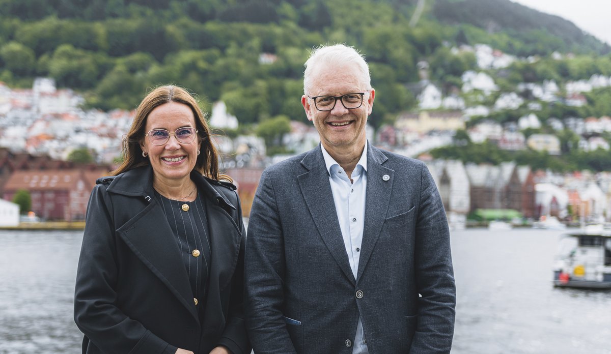 bilde av to personer som står med Bryggen i Bergen i bakgrunnen.