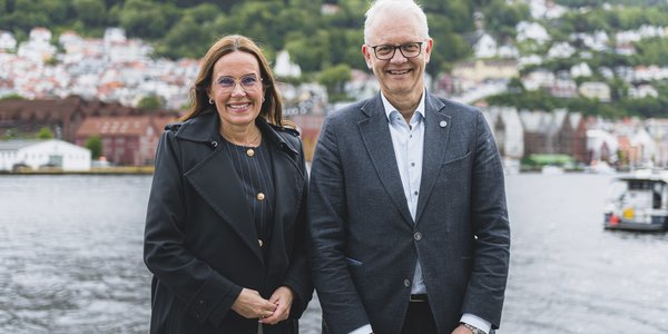 

bilde av to personer som står med Bryggen i Bergen i bakgrunnen.