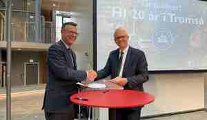 to menn håndhilser og smiler mot publikum fra en scene