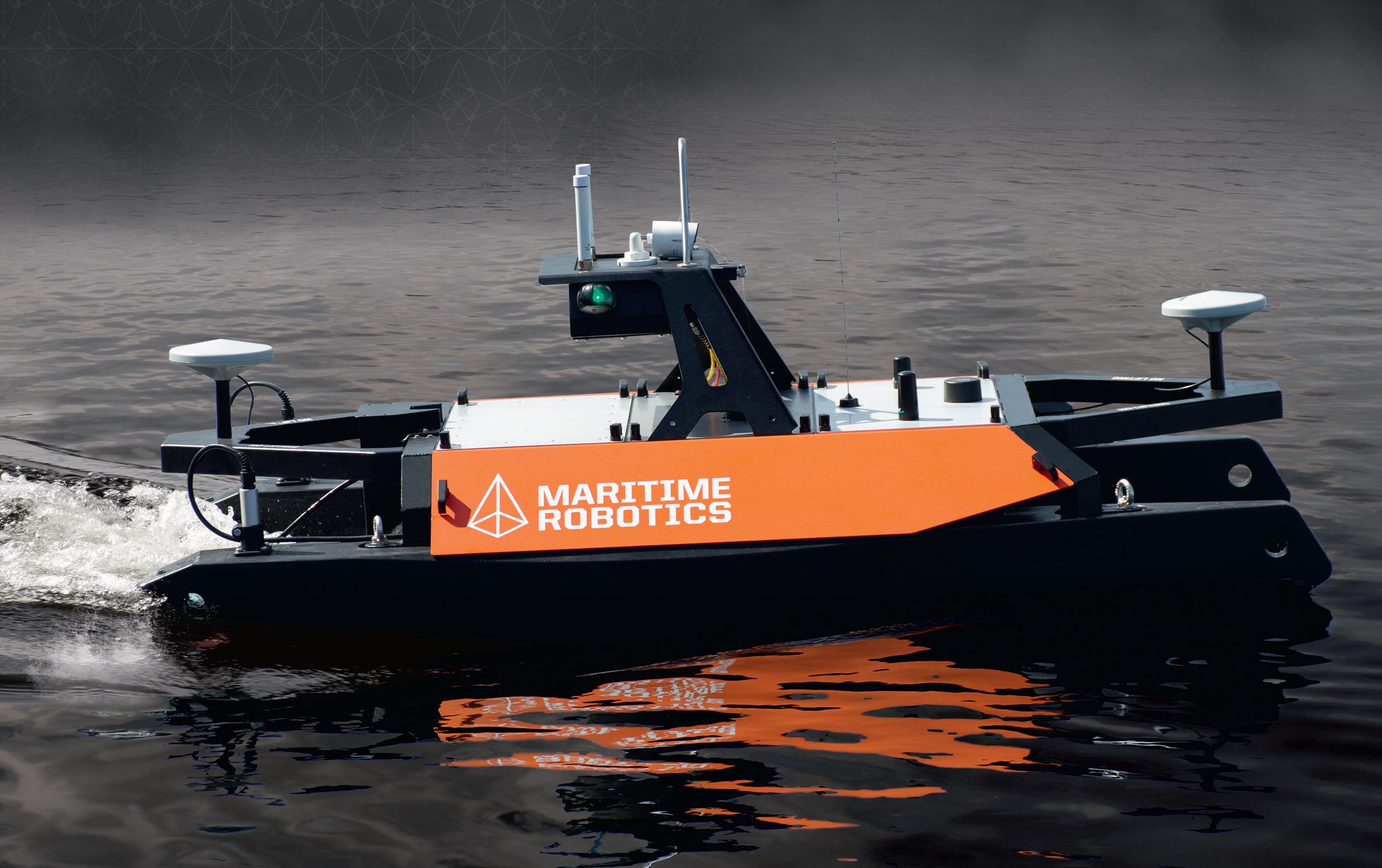 Picture of the Otter (Maritime Robotics) a black and orange catamaran, with an electric motor, with antennas in the bow, aft and on the roof.