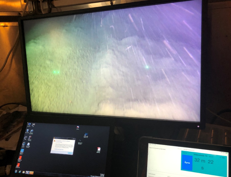På bildet ser vi en av skjermene som direkteoverfører fra videosleden. Vi ser at det filmes over muddermunn. Toktloggeren vises på egen skjerm og viser at filmingen har foregått i 32 minutter og 22 sekunder.