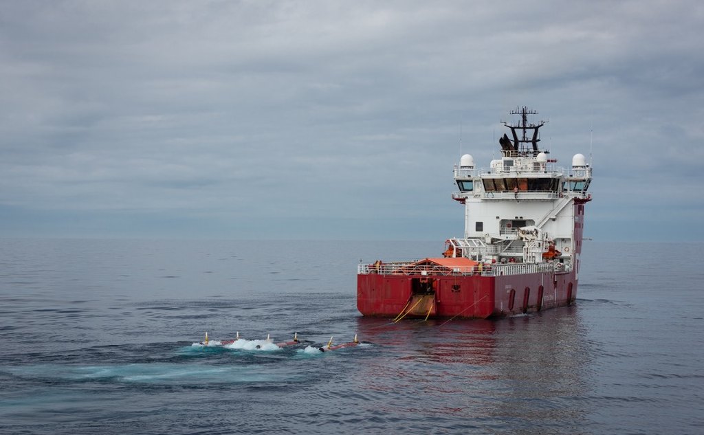 foto av en supplybåt med torpedolignende gjenstander på slep i overflaten